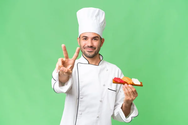 Junger Kaukasischer Koch Hält Lächelnd Ein Sushi Vor Isoliertem Hintergrund — Stockfoto