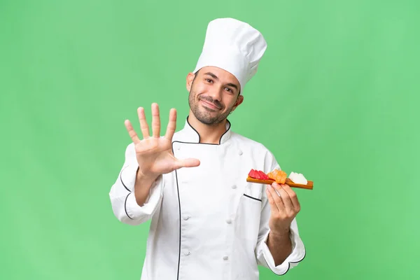 Junger Kaukasischer Koch Hält Ein Sushi Über Isolierten Hintergrund Und — Stockfoto