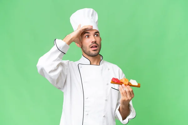 Ung Kaukasisk Kock Håller Sushi Över Isolerad Bakgrund Gör Överraskning — Stockfoto