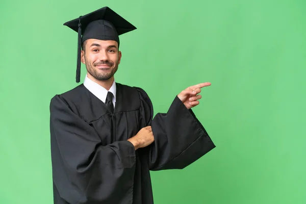 Νεαρός Απόφοιτος Πανεπιστημίου Άνθρωπος Πάνω Από Απομονωμένη Υπόβαθρο Δείχνοντας Δάχτυλο — Φωτογραφία Αρχείου