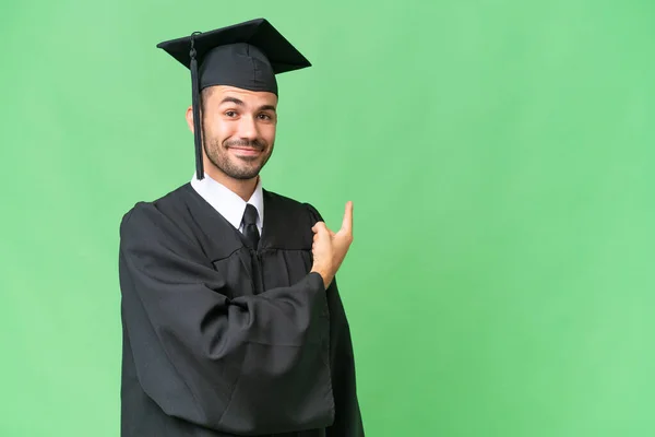 Jovem Universitário Graduado Homem Sobre Isolado Fundo Apontando Para Trás — Fotografia de Stock