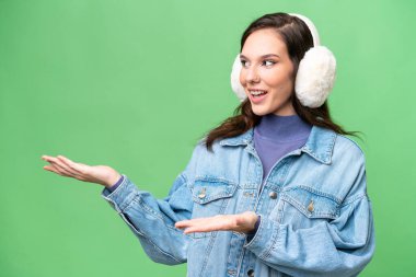 İzole edilmiş arka planda kışın kuklalar takan beyaz bir kadın. Şaşırtıcı bir yüz ifadesi var.