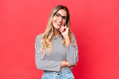 Genç Uruguaylı kadın kırmızı arka planda izole edilmiş gülüyor.