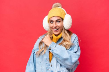 Genç, güzel Uruguaylı bir kadın, kırmızı arka planda izole edilmiş kış kürkleri giyip zaferi kutluyor.