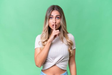 Genç Uruguaylı kadın, izole edilmiş arka planda parmağını ağzına koyan sessiz bir jest işareti gösteriyor.