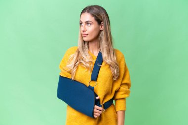 Kırık kollu genç Uruguaylı kadın ve izole edilmiş arka planda askısı var.