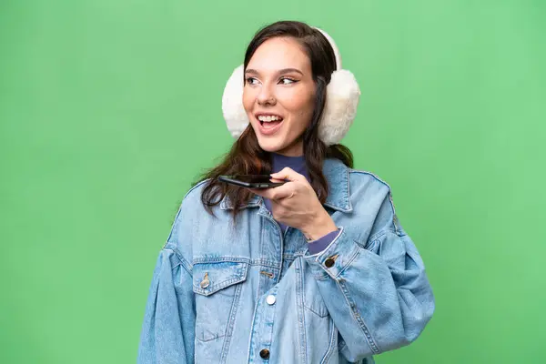 Молодая Белая Женщина Зимних Муфтах Изолированном Фоне Поддерживает Разговор Мобильным — стоковое фото