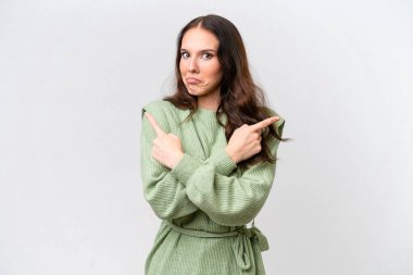 Beyaz arka planda izole edilmiş genç beyaz kadın, yan taraftakilerin şüphelerine işaret ediyor.