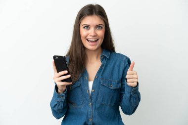 Young caucasian woman isolated on white background using mobile phone while doing thumbs up