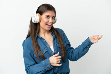 Beyaz arka planda izole edilmiş beyaz bir kadın müzik dinliyor ve gitar hareketi yapıyor.