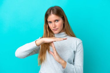 Mavi arka planda izole edilmiş genç sarışın bir kadın.