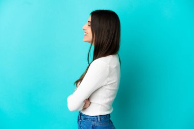 Genç beyaz kadın, mavi arka planda, yan pozisyonda izole edilmiş.