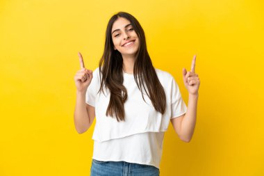 Sarı arka planda izole edilmiş beyaz bir kadın harika bir fikre işaret ediyor.