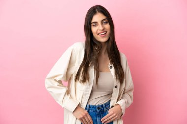 Pembe arka planda izole edilmiş genç beyaz kadın gülüyor.