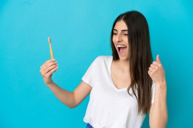 Mavi arka planda dişlerini fırçalayan beyaz bir kadın zaferi kutluyor.