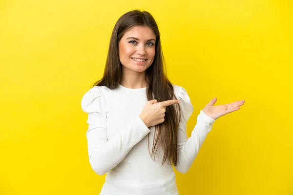 Young Caucasian Woman Isolated Yellow Background Holding Copyspace Imaginary Palm — Stock Photo, Image