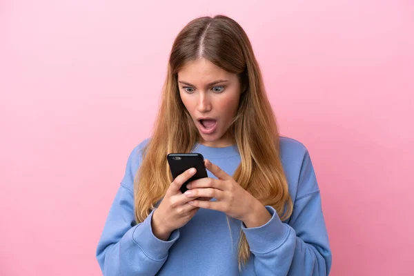 Молодая Блондинка Изолирована Розовом Фоне Глядя Камеру Используя Мобильный Телефон — стоковое фото