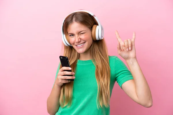Νεαρή Ξανθιά Γυναίκα Απομονωμένη Ροζ Φόντο Ακούγοντας Μουσική Μια Κινητή — Φωτογραφία Αρχείου