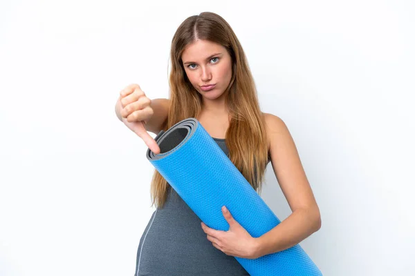 年轻的女运动员一边去上瑜伽课 一边拿着垫子 带着负面的表情展示着大拇指 — 图库照片