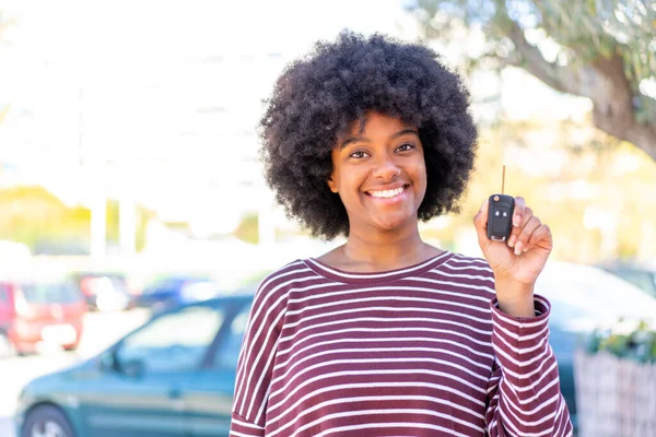 African American girl holding car keys at outdoors smiling a lot