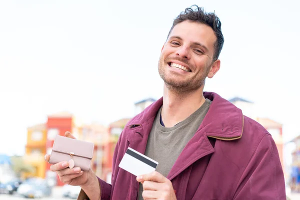 Young Caucasian Man Outdoors Holding Wallet Credit Card Happy Expression — Stock Photo, Image