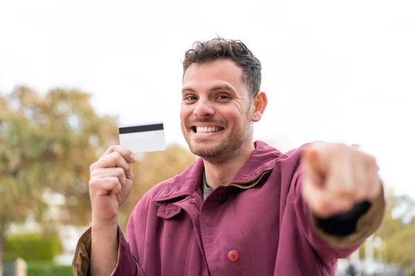 Ung Kaukasier Man Som Håller Ett Kreditkort Utomhus Pekar Finger — Stockfoto