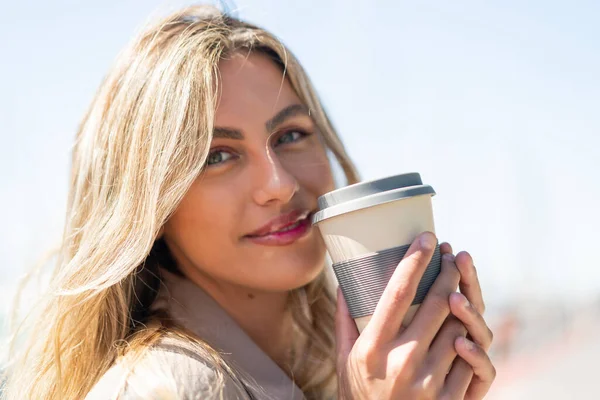 年轻漂亮的金发乌拉圭女人在户外拿着咖啡 — 图库照片