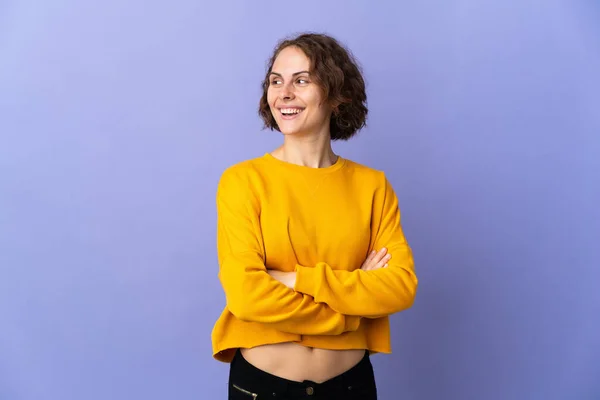 Young English woman isolated on purple background with arms crossed and happy