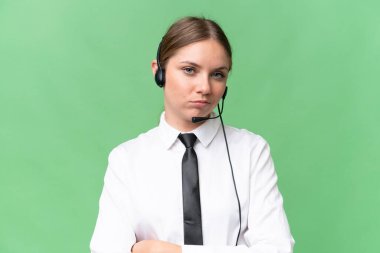 Tele pazarlamacı beyaz kadın üzgün bir ifadeyle izole edilmiş arka planda bir kulaklıkla çalışıyor.