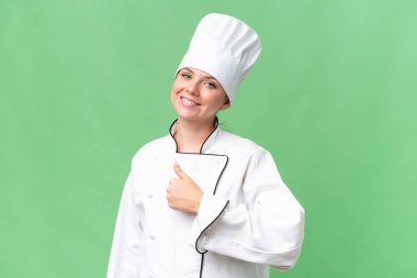 Genç aşçı kadın izole edilmiş yeşil arka plan 