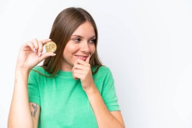 Beyaz arka planda izole edilmiş Bitcoin tutan güzel sarışın kadın bir fikir üretiyor ve bakıyor.