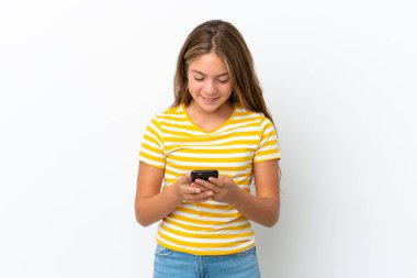 Beyaz arka planda izole edilmiş küçük beyaz kız cep telefonuyla bir mesaj gönderiyor.