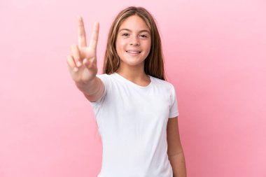 Little caucasian girl isolated on pink background smiling and showing victory sign