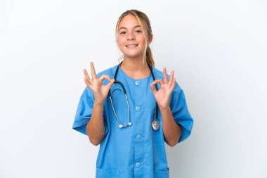 Beyaz arka planda cerrah kılığına girmiş küçük beyaz kız parmaklarıyla iyi bir işaret gösteriyor.