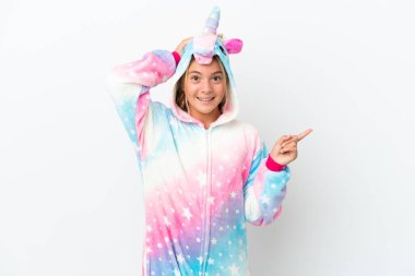 Beyaz arka planda izole edilmiş, tek boynuzlu at pijamalı küçük bir kız şaşırmış ve parmağıyla kenarı işaret ediyor.