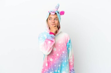 Beyaz arka planda izole edilmiş tek boynuzlu at pijamalı küçük kız yan tarafa bakıyor.