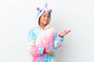 Beyaz arka planda izole edilmiş tek boynuzlu pijamalı küçük bir kız. Davet edilmek için ellerini yana uzatıyor.