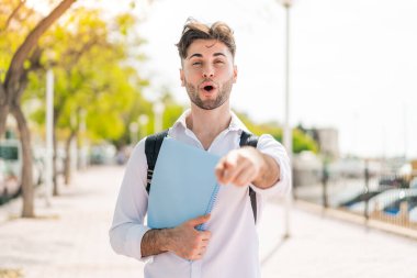 Dışarıdaki yakışıklı genç adam şaşırmış ve ön tarafı işaret ediyor.