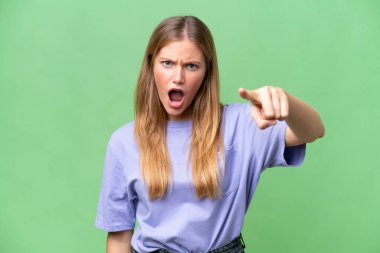 İzole edilmiş arka planda genç ve güzel bir kadın hayal kırıklığına uğramış ve ön tarafı işaret ediyor.