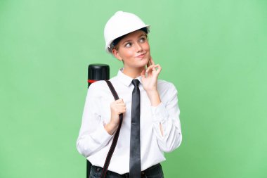 Miğferli, beyaz, genç bir kadın izole edilmiş bir arka plan üzerinde planlar tutuyor.