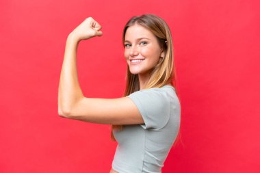 Kırmızı arka planda izole edilmiş güzel bir kadın güçlü bir jest yapıyor.