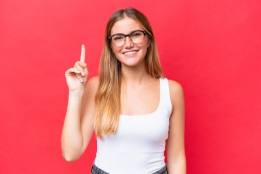 Kırmızı arka planda izole edilmiş güzel bir kadın harika bir fikre işaret ediyor.