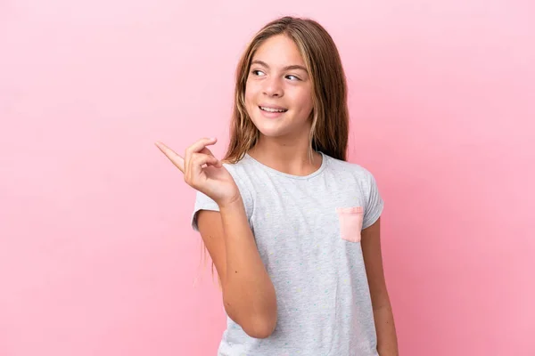 ピンクの背景に隔離された小さな白人の女の子は指を持ち上げながら解決策を実現しようとしている — ストック写真
