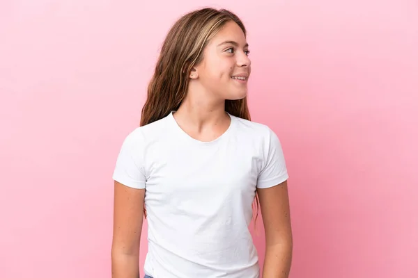 Pequena Menina Caucasiana Isolado Fundo Rosa Olhando Para Lado Sorrindo — Fotografia de Stock