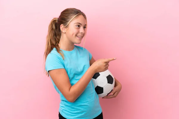 小さなサッカー選手の女の子はピンクの背景指差し指で側面に分離し 製品を提示 — ストック写真