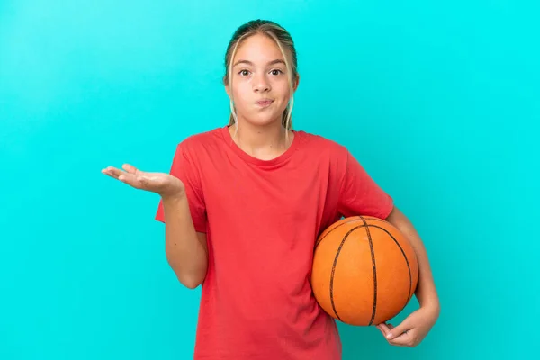 小さなCaucasian女の子プレイバスケットボール孤立した上に青の背景に疑問を持ちながら手を上げる — ストック写真