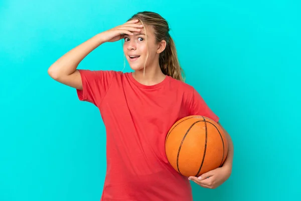 小さいですCaucasian女の子遊びますバスケットボール孤立しました上の青の背景あります驚くべきジェスチャーをしながら側面を見ます — ストック写真