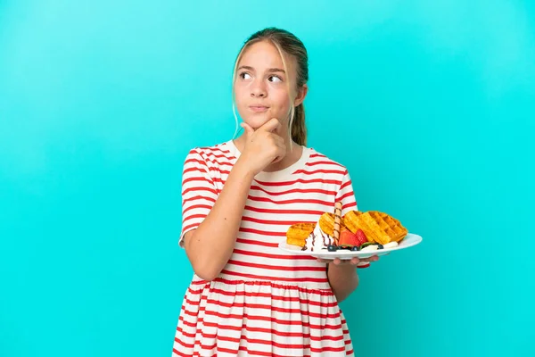 Little Caucasian Girl Holding Waffles Isolated Blue Background Having Doubts — Stock Photo, Image