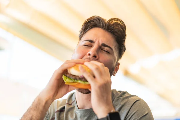 Fiatal Jóképű Férfi Kezében Egy Hamburger — Stock Fotó