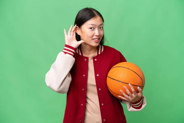 Jonge Basketbalspeler Aziatische Vrouw Geïsoleerde Achtergrond Luisteren Naar Iets Door — Stockfoto